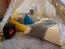 グランピングテント内の寝室スペース。白を基調としたデザインで、可愛い家具と照明が映えます。