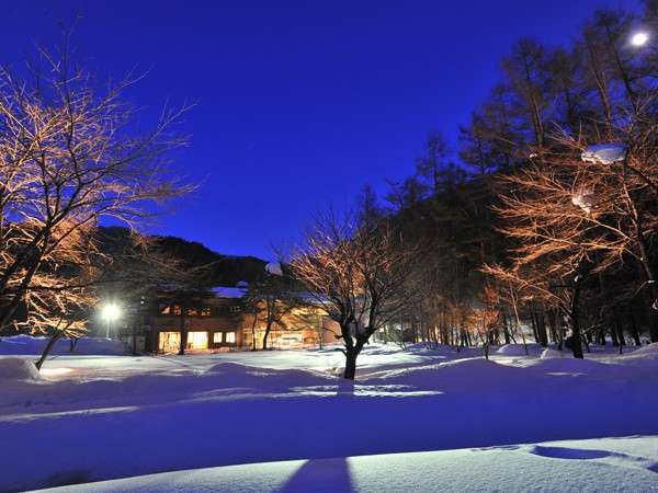【冬】真っ白な雪景色の中、月明かりに照らされる宿風景。雪見風呂も楽しめる季節、夜の露天風呂も趣がある