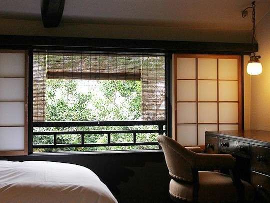 窓際から伸びる勾配天井の梁が美しい寝室。窓からは坪庭の緑が望めます。