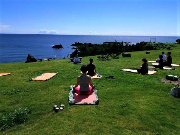 芝生の上で心地よい潮風を浴びながらの朝ヨガ