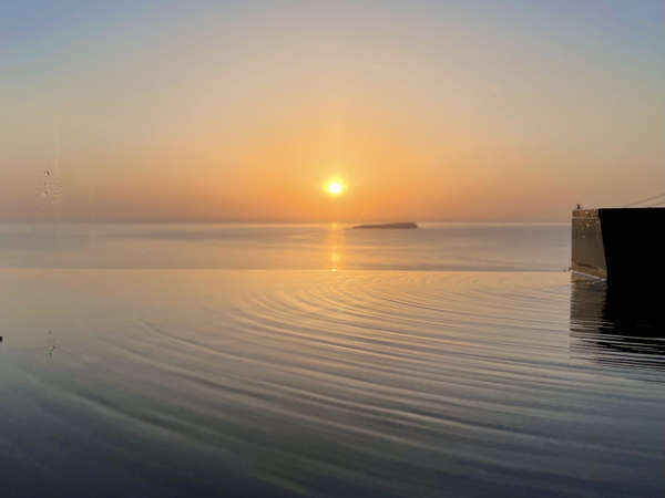 温泉から眺める日の出。湯面の向こうに繋がる海から昇る朝日