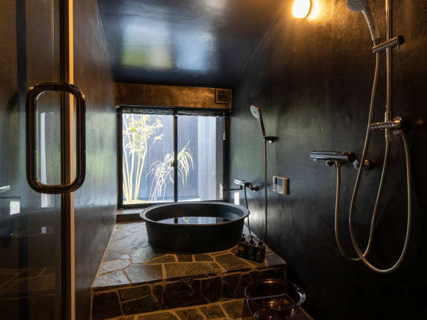枯山水の庭を望み、五右衛門風呂風の浴槽が特徴的な浴室。露天風呂のような雰囲気を味わっていただけます。