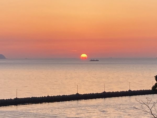 水平線に沈む夕日と突堤（4月中旬）