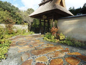 「京都　湯の花温泉　すみや亀峰菴」の版築の土塀と　茅葺き門　のどこか懐かしい風景がお客様をお出迎えします