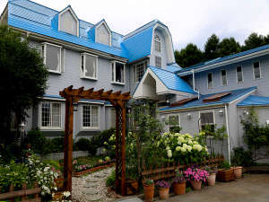 「ペンション　ラヴィン　スプーンフル」の青い屋根にパステルグレーの壁、そして木製アーチが目印
