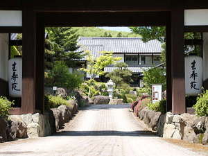 「わらしの宿　生寿苑」の宿の門から見た母屋。門をくぐると、生寿苑の世界が広がります。