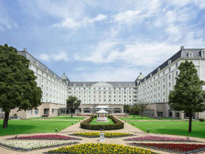 「ホテル日航ハウステンボス」の青い空と緑の木々が白亜のホテルと優しく調和したロケーションを作ります。