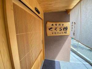 「旅宿松本やぐら禅」の樅ノ木に書き下ろされた館名文字。大きな桧製の自動ドアがお客様をお迎えします。