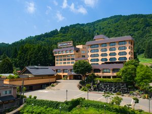 「越後湯沢温泉　湯沢グランドホテル」の【施設外観（夏）】便利な駅前ながら自然に囲まれた旅館です。駅から歩いて3分の好立地も魅力です。
