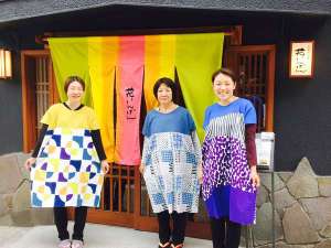 「草津温泉　お豆の小宿　花いんげん」のカラフル暖簾の前で若女将とスタッフで「ハイ、チーズ！！」