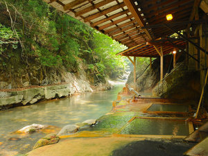 【混浴　川岸露天風呂】鹿股川そして対岸の木々と一体になれる明賀屋本館自慢の温泉をお楽しみください。