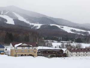 「リゾートイン　ノースカントリー」の冬の外観　後ろに見渡すのは富良野スキー場