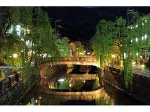 温泉街の中央を流れる大谿川の川沿いがライトアップされると、柳と太鼓橋が水面に浮かび上がります。