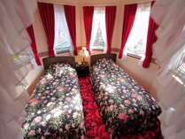 赤の絨毯とカーテンそして黒をベースにしたサンダーソンのベッドカバーが優雅さと落ち着きを感じる。