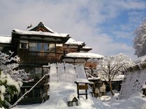 【冬の外観】すっぽりと雪に覆われた嵐渓荘。夜は温かな明かりが灯ります。