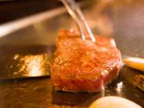 目の前の鉄板で調理されるステーキ
