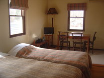 Wベッド１台とシングルベッド１台。３畳の絨毯敷にはテーブルがあります。