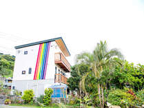 ・＜外観＞白い壁に描かれた虹が印象的な建物 写真