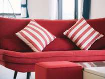 *［客室一例］お部屋のアクセントになっている赤いソファー