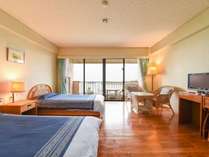 *［洋室ツイン］シングルベッドを配した客室。緑の芝とエメラルドグリーンの海が広がります。