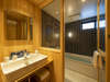 ヒノキ板に囲まれた明るい雰囲気の洗面台、大きな浴槽やシャワーを備えた浴室。